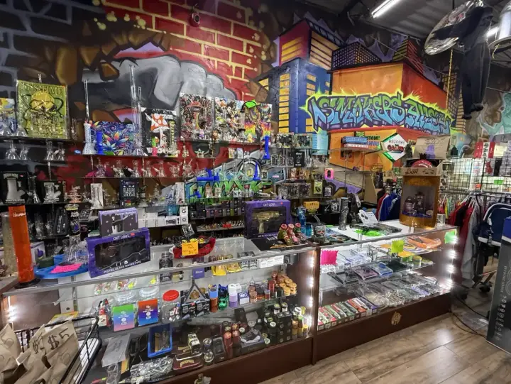 Tall glass water pipes and bongs on the glass shelves under the painted Smokers Alley mural at Smoker's Alley Gallery, 13 Mile and Little Mack, Roseville